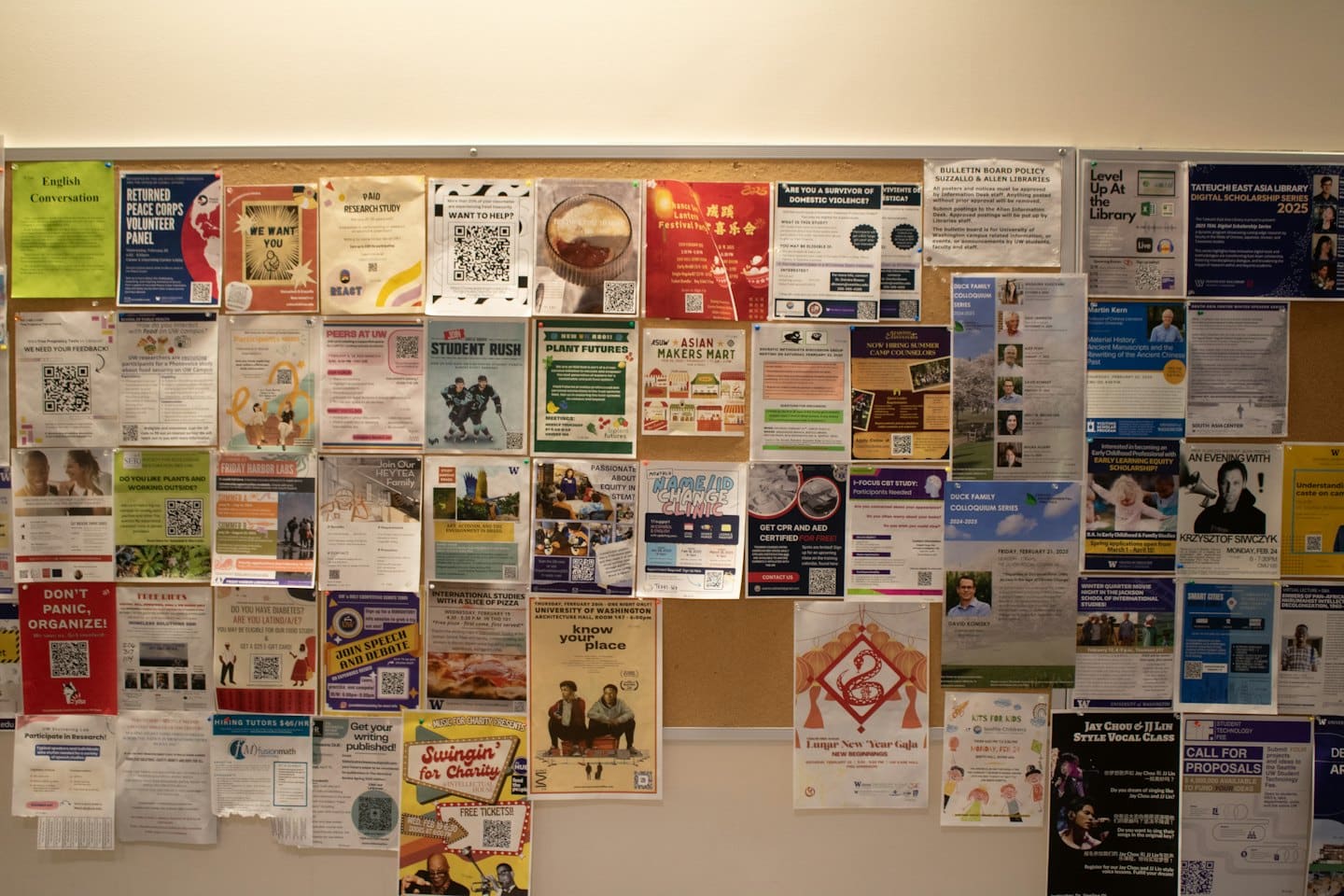Bulletin board covered in colorful flyers at a university.